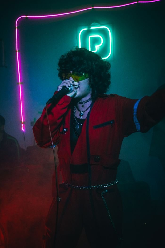 Dynamic photo of a singer passionately performing with neon lights at a party.