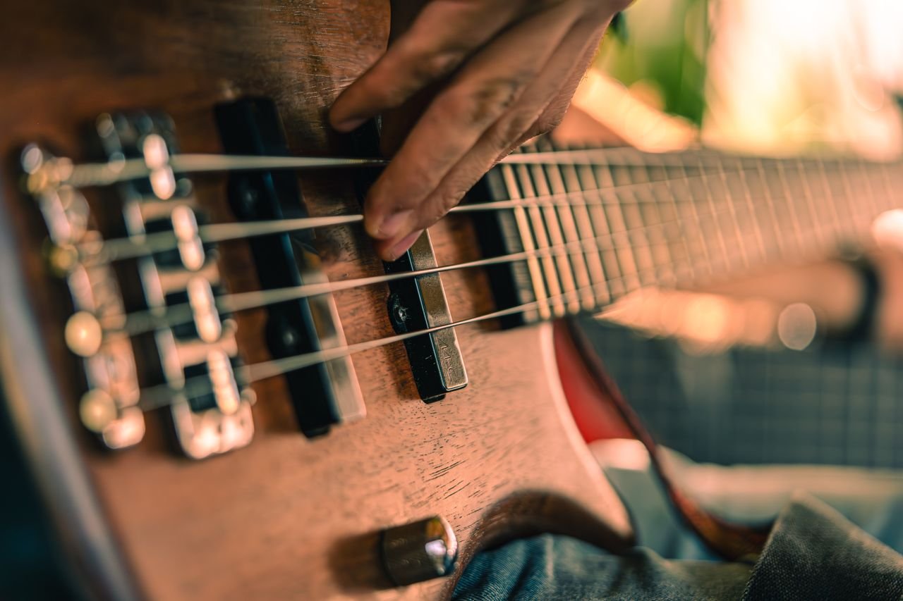 A detailed shot of a musician playing a bass guitar, showcasing musical performance intensity.