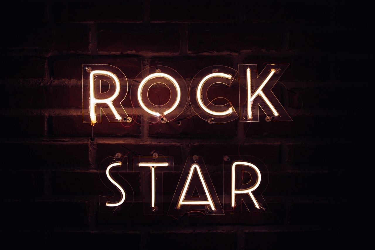 Brightly lit neon sign with the words 'Rock Star' on a brick wall, creating a vibrant retro vibe.